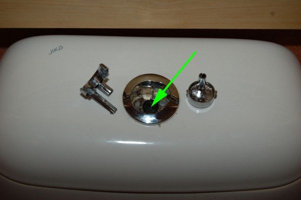 Реже встречается другой способ фиксации кнопки: нужно извлечь отверткой нажимную часть, скрывающую гайку.